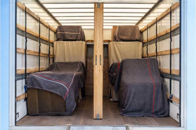 Intérieur d'une caisse de camion séparée en deux par une cloison de calage, un lot sous housse de chaque côté