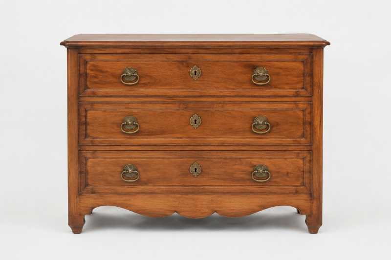 Commode ancienne en bois ciré, seule au centre d'un fond neutre clair, éclairée de face