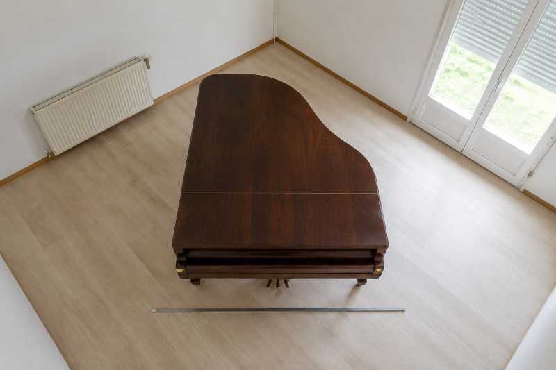 Piano à queue couvercle fermé vu de dessus, mètre ruban déroulé au sol dans le sens de la largeur