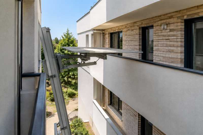 Tête de monte-meuble arrêtée au niveau d'un balcon filant à garde-corps plein, plateau vide